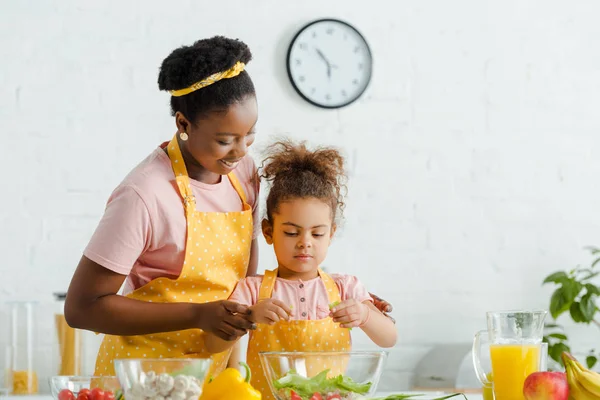 Happy african american mother and kid preparing salad — Stock Photo