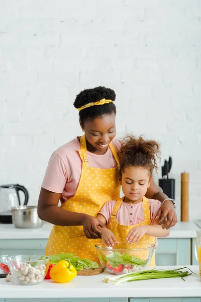 Alegre africano americano madre y niño preparación ensalada - foto de stock