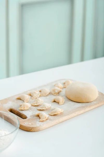 Farine près de boulettes crues sur planche à découper en bois — Photo de stock