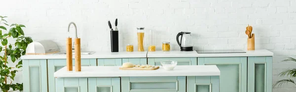 Панорамный снимок необработанных пельменей на деревянной доске возле чаши с мукой на кухне — стоковое фото