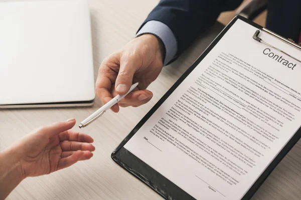 Vista recortada del agente dando pluma a la mujer y sujetando portapapeles con letras de contrato — Stock Photo