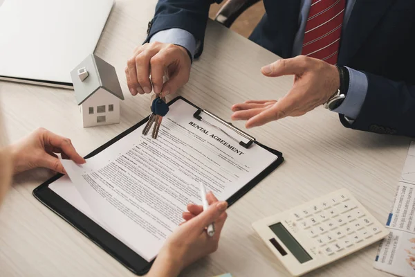 Vista recortada de la mujer cerca del portapapeles con el contrato de alquiler de letras y llaves de tenencia corredor - foto de stock