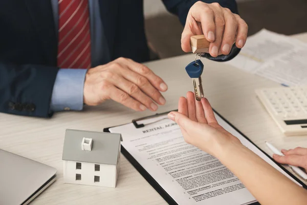 Ausgeschnittene Ansicht des Agenten, der dem Kunden Schlüssel in der Nähe der Zwischenablage mit Dokument und Kartonhaus-Modell übergibt — Stockfoto