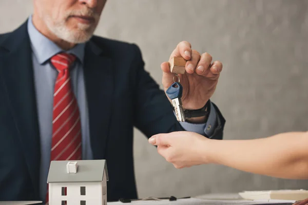 Ausgeschnittene Ansicht eines Agenten, der dem Kunden Schlüssel in der Nähe von Kartonhaus übergibt — Stockfoto