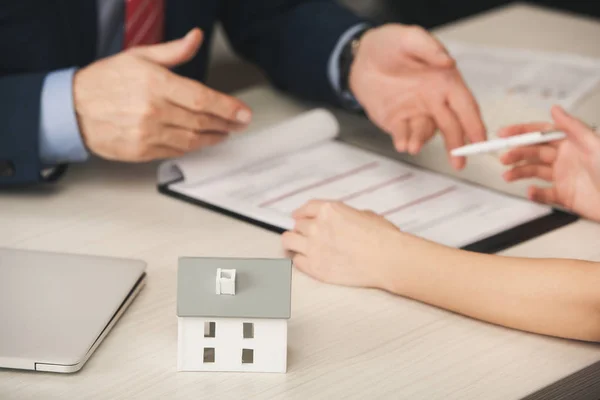 Selective focus of carton house model near agent and woman in office — Stock Photo