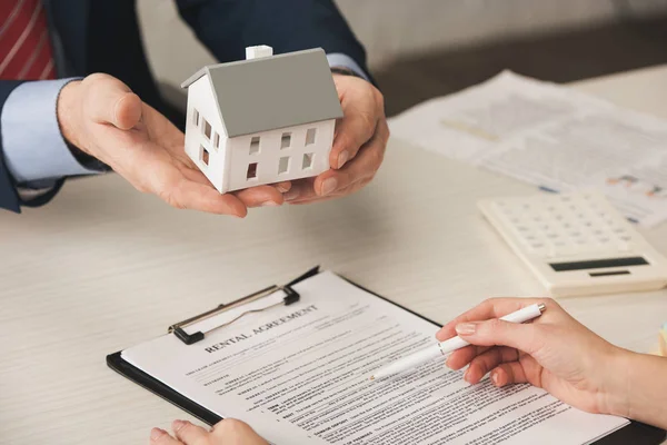 Vue recadrée de l'agent tenant modèle de maison près de la femme avec stylo à la main — Photo de stock