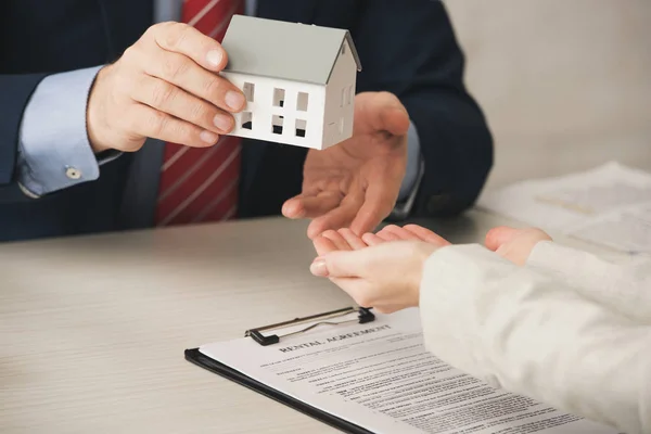 Cropped view of agent giving house model to woman with cupped hands — Stock Photo