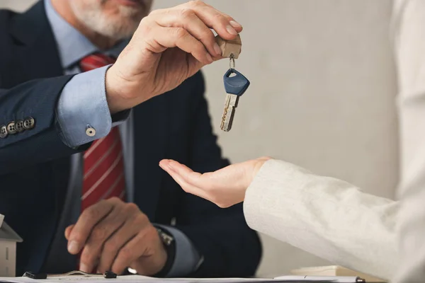 Vista ritagliata di agente immobiliare dando la chiave alla donna in ufficio — Foto stock