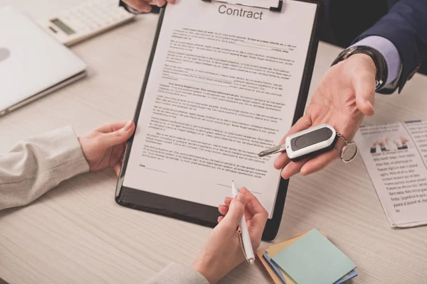 Cropped view of agent holding car key near client and contract — Stock Photo