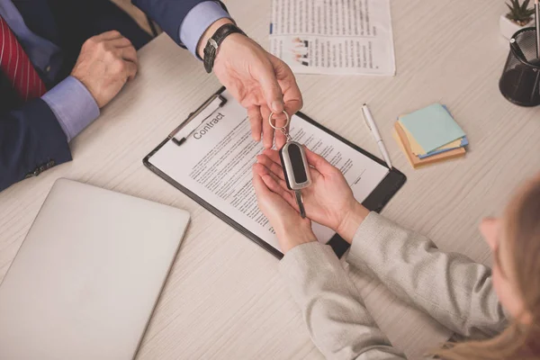 Top view of agent giving car key to client near clipboard with contract — Stock Photo