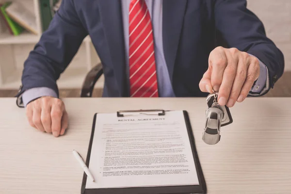 Selective focus of agent holding car key near rental agreement — Stock Photo