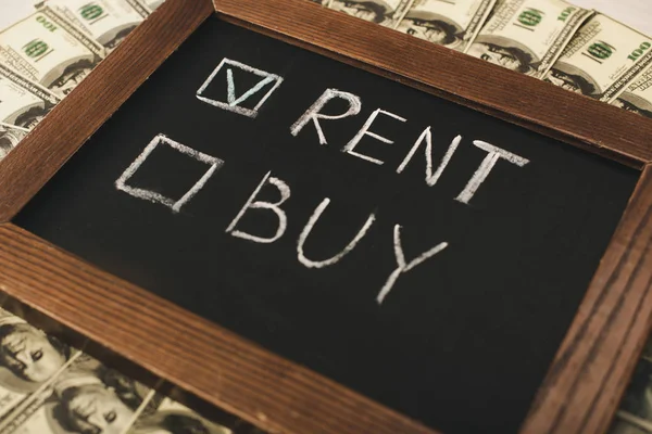 Top view of chalkboard with rent and buy lettering near cash — Stock Photo