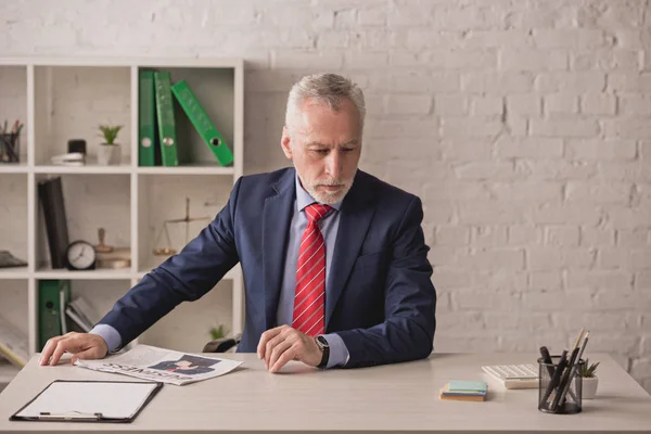 Bearded realtor looking at desk with clipboard and stationery — Stock Photo