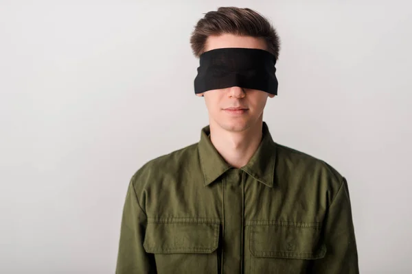 Joven hombre con los ojos vendados aislado en blanco, concepto de derechos humanos - foto de stock