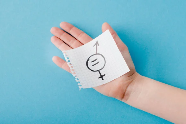 Top view of woman holding paper with gender equality symbol isolated on blue — Stock Photo