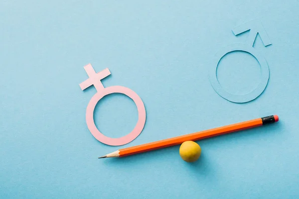 Pequeña bola y lápiz con diferentes géneros aislados en azul, concepto de igualdad sexual - foto de stock