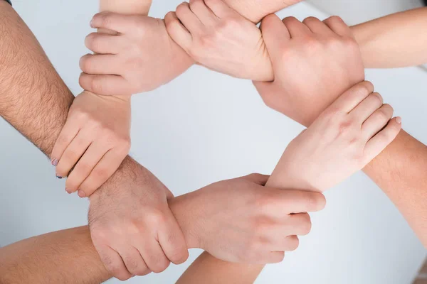 Visão superior de mulheres e homens com as mãos unidas sobre branco, conceito de direitos humanos — Fotografia de Stock