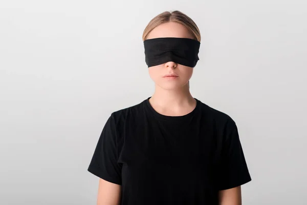 Blindfolded young woman in black t-shirt isolated on white, human rights concept — Stock Photo