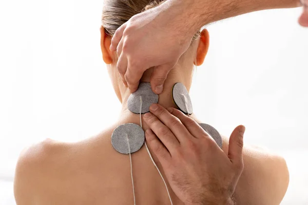 Therapeut befestigt Elektroden am Hals des Patienten während der Elektrotherapie isoliert auf weiß — Stockfoto