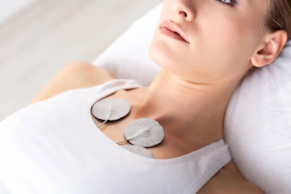 Vista ritagliata di giovane donna sdraiata sul divano da massaggio durante il trattamento con elettrodi — Foto stock