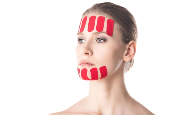 Bella donna con nastri di cinesiologia sul viso guardando lontano isolato su bianco — Stock Photo