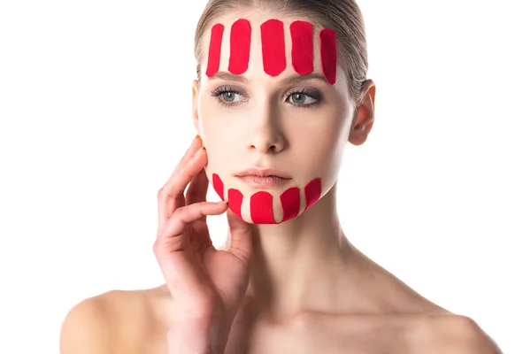 Mujer joven con cintas de kinesiología en la cara mirando hacia otro lado aislado en blanco - foto de stock