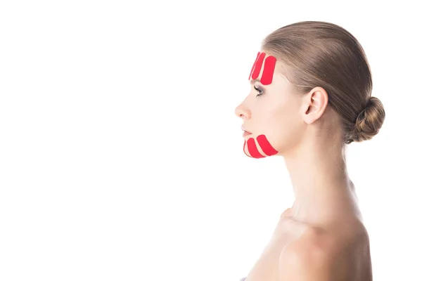 Vista laterale di nastri di cinesiologia su mento e fronte di bella ragazza isolata su bianco — Stock Photo