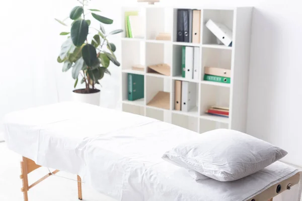 Sofá de masaje vacío con almohada en la clínica - foto de stock