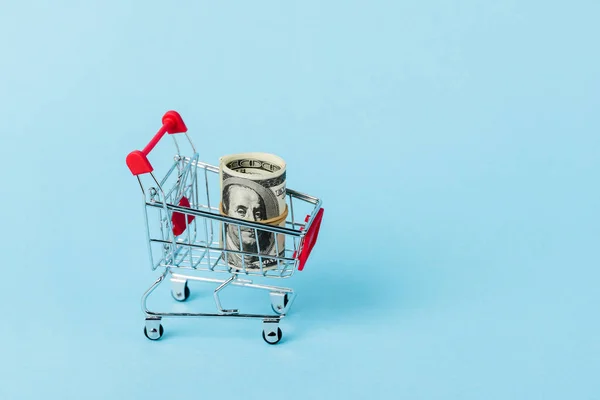 Toy shopping trolley with dollar banknotes on blue, leasing concept — Stock Photo