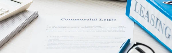 Plano panorámico de la carpeta cerca del documento con letras de arrendamiento comercial en el escritorio - foto de stock