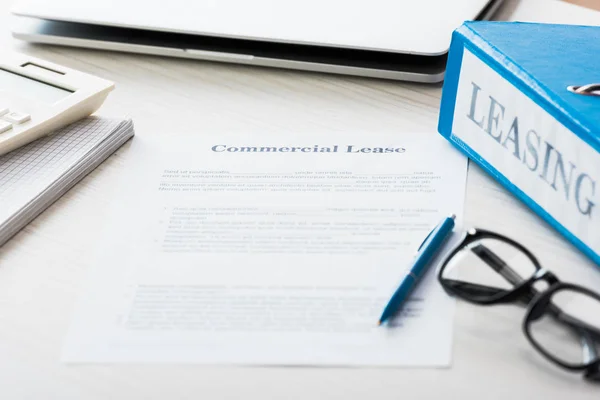 Selective focus of folder near document with commercial lease lettering on desk — Stock Photo