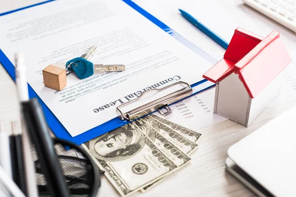 Selective focus of document with commercial lease lettering on clipboard near keys, house model and money — Stock Photo