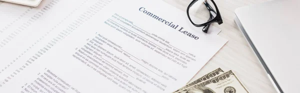 Panoramic shot of documents with commercial lease lettering near money and glasses on desk — Stock Photo