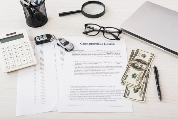 Dokument mit gewerblichem Leasingaufdruck in der Nähe von Spielzeugauto, Geld, Taschenrechner, Lupe, Laptop und Brille — Stockfoto