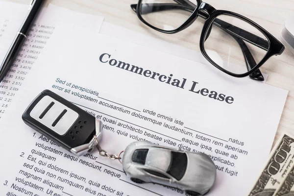 Vue du dessus du document avec le lettrage commercial de bail près de la voiture de jouet, argent et lunettes — Photo de stock