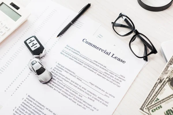 Vue du haut du document avec lettrage de location commerciale près de la voiture jouet, stylo, argent et lunettes — Photo de stock