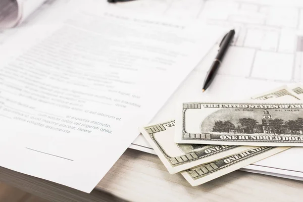 Селективный фокус долларовых банкнот рядом с документами и ручкой на столе — стоковое фото