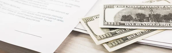 Prise de vue panoramique des billets en dollars près des documents et stylo sur le bureau — Photo de stock