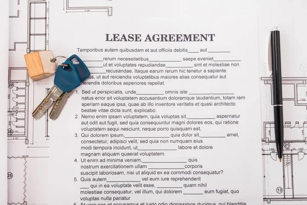 Top view of document with lease agreement lettering near blueprints, pen and keys on desk — Stock Photo