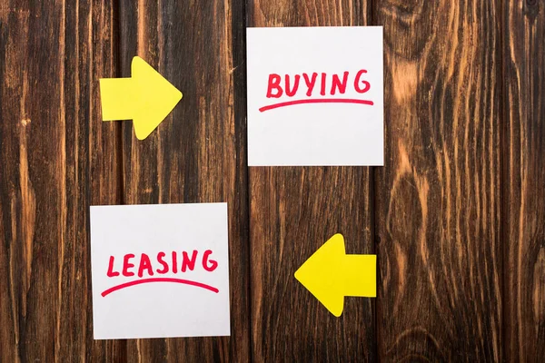 Top view of papers with buying and leasing lettering on wooden surface — Stock Photo