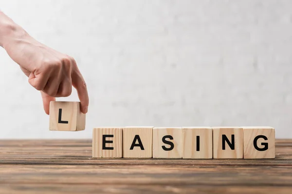 Cropped view of man holding wooden cube with lettering on white — Stock Photo