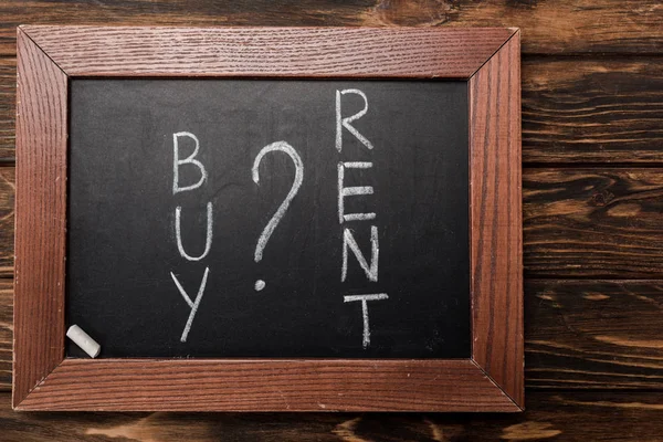 Top view of chalkboard with buy and rent lettering on wooden surface — Stock Photo