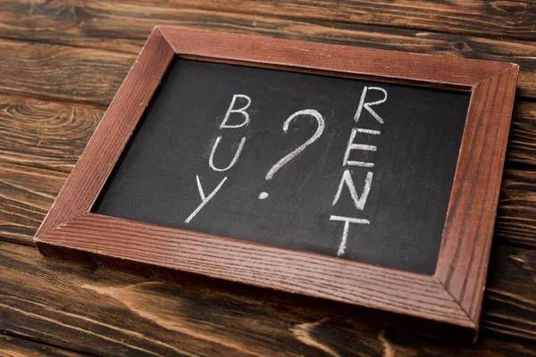 Chalkboard with buy and rent lettering on wooden surface — Stock Photo