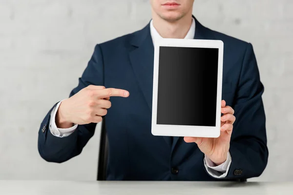 Vista recortada de agente inmobiliario en traje apuntando con el dedo a la tableta digital con pantalla en blanco - foto de stock