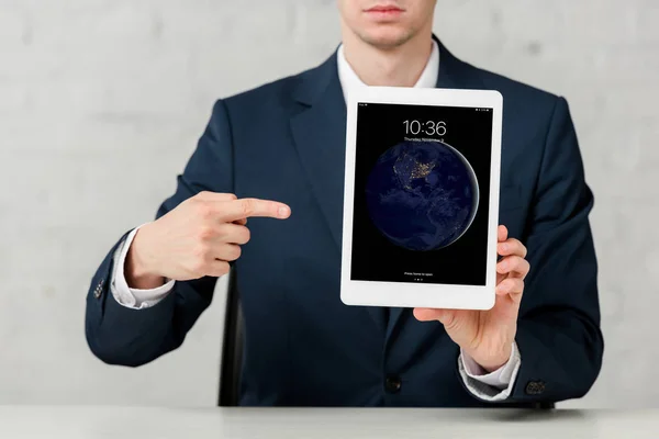 Cropped view of realtor in suit pointing with finger at ipad on white — Stock Photo