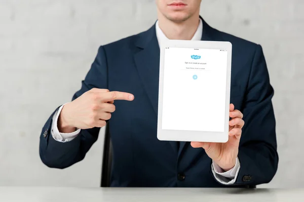 Vue recadrée de l'agent immobilier en costume pointant avec le doigt à la tablette numérique avec l'application skype sur blanc — Photo de stock