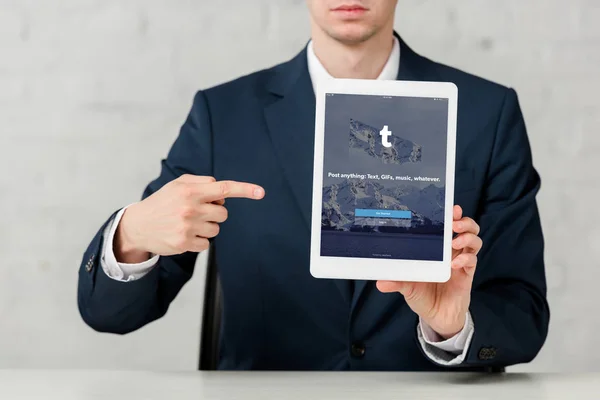 Cropped view of realtor in suit pointing with finger at digital tablet with tumblr app on white — Stock Photo