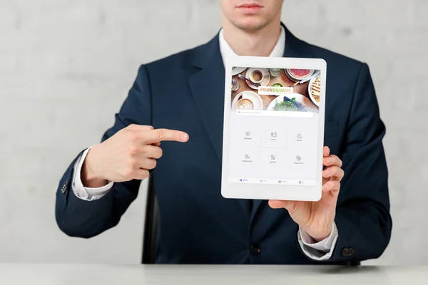Vue recadrée de l'agent immobilier en costume pointant avec le doigt à la tablette numérique avec application quadratique sur blanc — Photo de stock