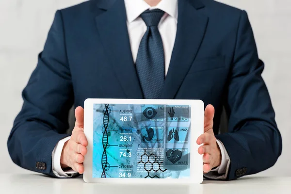 Cropped view of businessman in suit holding digital tablet with medical app on white — Stock Photo