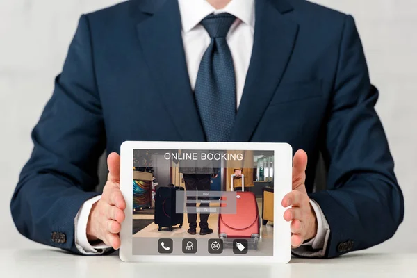 Vue recadrée de l'homme d'affaires tenant tablette numérique avec réservation en ligne à l'écran sur blanc — Photo de stock